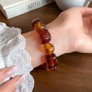 Detailed view of amber acrylic irregular geometric beaded bracelet on a woman's wrist