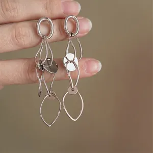 Close-up detail of fashionable silver-tone hollow-out circular tassel drop earrings