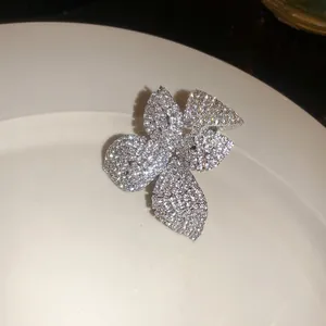 Primer plano de un pendiente de clip con forma de flor y pedrería sobre un plato blanco