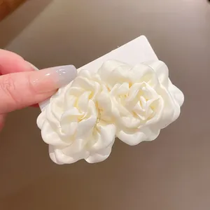 Makro-Detail einer eleganten cremefarbenen Satinrosen-Haarspange auf einer Karte