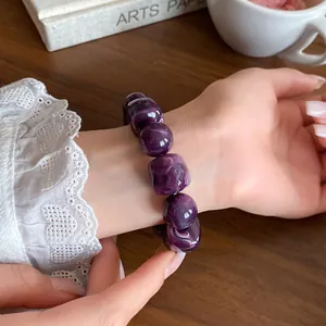 Detail shot of a purple acrylic geometric beaded bracelet on a female wrist.