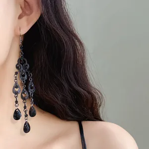 Close-up of black gothic chandelier earrings with waterdrop rhinestones and tassels.