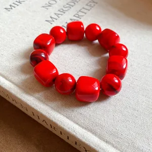 Macro view of red acrylic beaded bracelet with marbled texture and geometric shapes