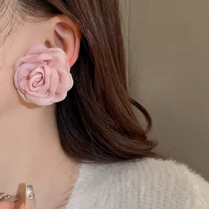Detailansicht eines süßen rosa Stoffrosen-Ohrrings im französischen Stil an einem Model.
