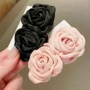Detailaufnahme von eleganten schwarzen und rosa Stoffrosen-Blütenclips auf Displaykarte.