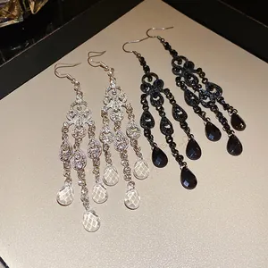 Detail of vintage-style chandelier earrings with hollow-out teardrops and tassel design.