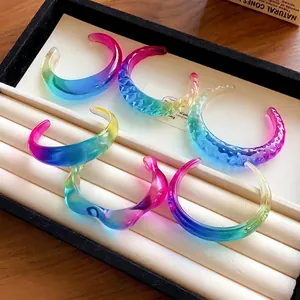 Detailed macro shot of various colorful gradient resin bangles in a jewelry tray.