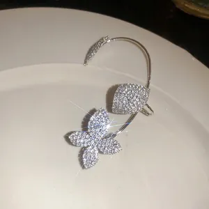 Primer plano de un pendiente trepador de mariposa brillante con pedrería de cristal.