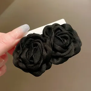 Nahaufnahme von eleganten schwarzen Stoffrosen-Haarspangen mit feiner Textur