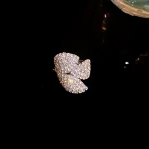 Primer plano macro de un pendiente de clip con forma de flor y pedrería sobre fondo negro