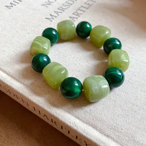 Detail view of green acrylic beaded bracelet with irregular marbled geometric textures.