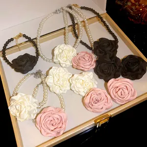 Detailansicht französischer Perlenketten mit großen Stoffrosen in einer Geschenkbox