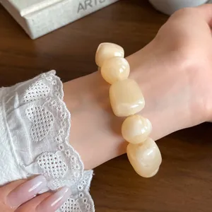 Creamy acrylic irregular geometric beaded bracelet worn with elegant lace sleeve