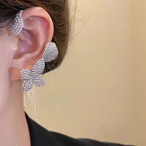 Vista detallada de un lujoso ear cuff con flores de pedrería plateada en la oreja