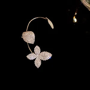 Primer plano de una joya de orejera con diamantes de imitación de mariposa y hoja plateada