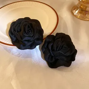 Nahaufnahme von eleganten handgefertigten schwarzen Stoffrosen-Ornamenten mit Satin-Textur