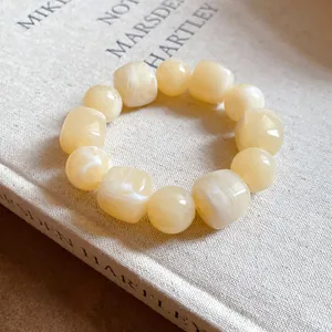 Close-up of cream acrylic beaded bracelet with irregular geometric marbled charms