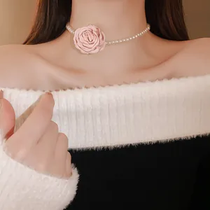 Nahaufnahme eines Kropfbandes mit rosa Stoffrose und Perlen am Hals eines Models.
