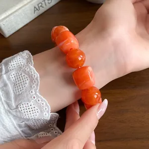 Close-up detail showing the texture of orange irregular acrylic geometric beaded bracelet on wrist.