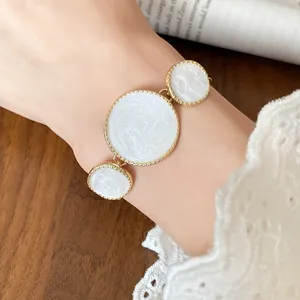 Detailed view of three white textured circular pendants with elegant gold-tone edges.