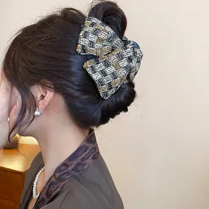 Close-up of elegant black and gold tweed fabric hair claw clip in a hair updo