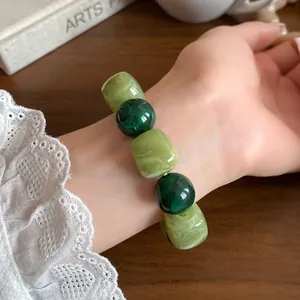 Detailed view of a chunky acrylic beaded bracelet in dark and light green tones