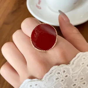 Close-up of a vintage wine red enamel ring with a gold-tone serrated border detail.