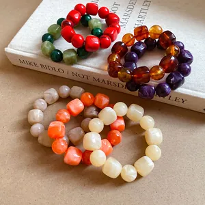 Detailed close-up view of colorful irregular acrylic chunky bead bracelets displayed on a book