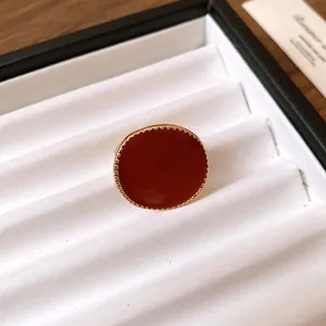 Close-up detail of a vintage style gold-toned ring featuring a deep red round enamel inlay