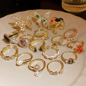Detailed close-up of various gold-plated rings featuring zircon, pearls and butterfly shapes