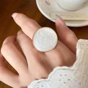 Close-up of a large white marbled circular ring with gold-toned vintage border