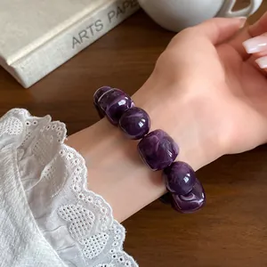 Detail view of a purple acrylic irregular geometric beaded bracelet on a wrist