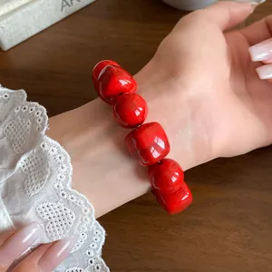 Close-up of red acrylic irregular geometric beaded bracelet on a woman's wrist