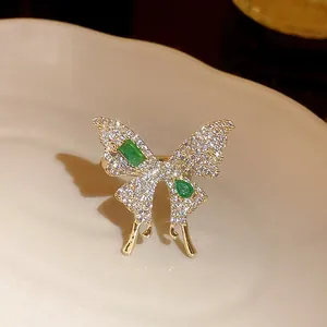 Close-up of elegant gold-plated butterfly ring with sparkling emerald green zircons