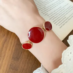 Close-up of French retro red enamel bracelet with irregular gold circular charms