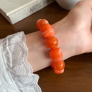 Close-up detail of an orange acrylic beaded bracelet featuring irregular geometric marble patterns