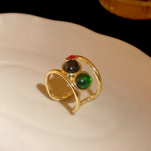 Close-up of a gold-plated snake-shaped open ring with red black and green stones