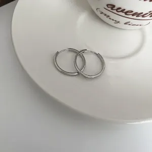Dettaglio ravvicinato di orecchini a cerchio in argento su un piattino di ceramica