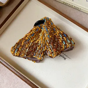 Close-up view of a stylish brown checkered tweed triangle hair claw clip on a tray.