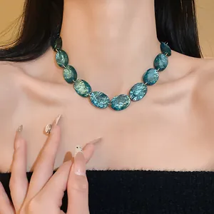 Detailed macro view of a vintage oval blue resin necklace worn on a woman's collarbone