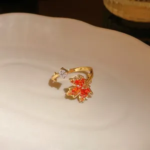 Close-up of a gold-plated maple leaf open ring with sparkling orange zircon stones