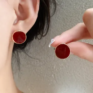 Detail of French vintage round stud earrings with red enamel and gold textured edge