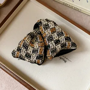 Close-up of a woven tweed triangular hair claw clip with black and gold checkered pattern