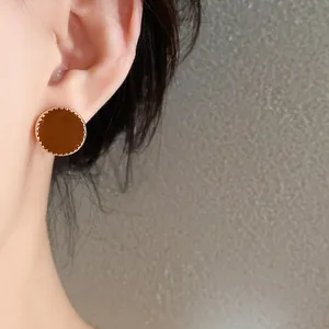 Close-up detail of an elegant retro brown round earring featuring a gold beaded outer edge