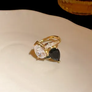 Macro detail of a high-end gold-plated ring featuring black and white pear-cut zircon stones