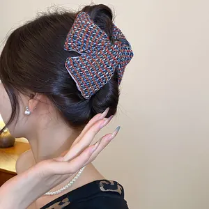 Detail view of multicolored tweed fabric plaid triangle hair claw clip on brunette hair