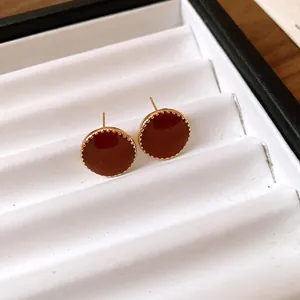 Detailed view of vintage gold-trimmed round stud earrings with deep red enamel finish