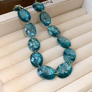 Close-up detail of a vintage oval teal resin bead necklace on a beige jewelry display