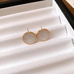 Close-up of elegant round gold stud earrings with pearlescent white inlay