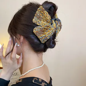 Detailed macro view of yellow tweed fabric bow hair claw clip worn on a bun